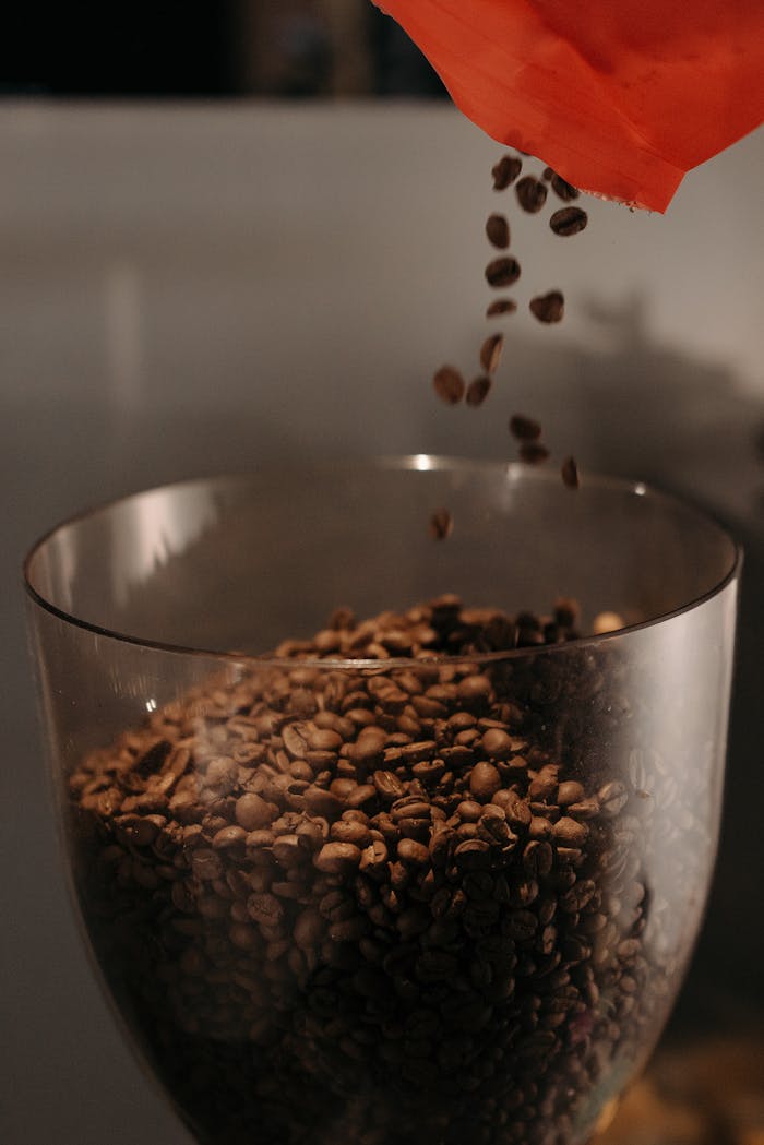 services-03 Close-up shot of aromatic coffee beans being poured into a glass bowl, emphasizing rich textures.